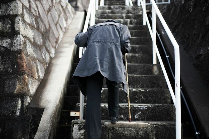 階段を上がる高齢女性