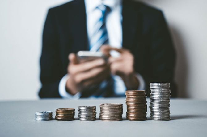 ビジネスマンの前に積まれたコイン