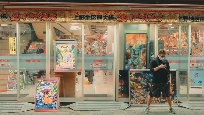 上野・アメ横のパチンコ店の前でマスクを着けた男性がスマホを操作している