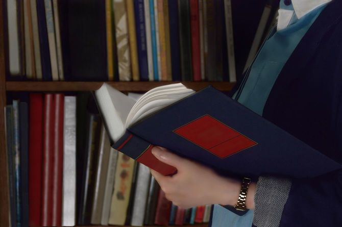 本棚の前で本を読む女性