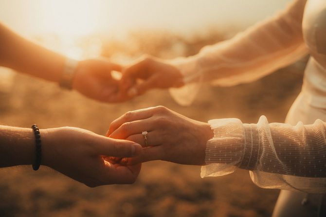 夕日の中で手をとる婚約中のカップル