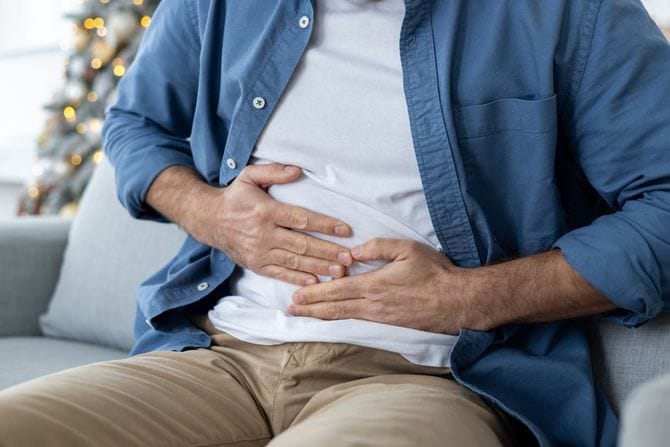 お腹に違和感を感じ手を当てている男性