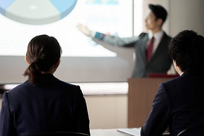 プレゼンテーションを聞くビジネスパーソン