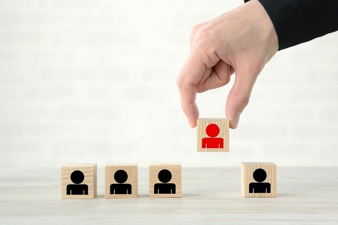 人間のピクトグラムで木製のブロックを選ぶビジネスマンの手