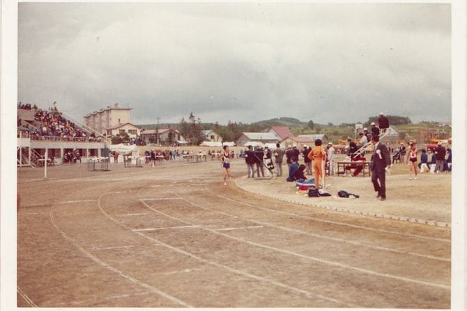 高校1年の全道高校陸上5000mで3位に入賞した筆者（左の紺色のユニフォームの選手）。筆者のほうを見ている決勝審判員の実父（白いキャップに上下白のウィンドブレーカー姿）