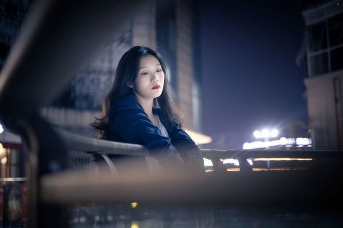 無表情で、夜の街を見つめる女性