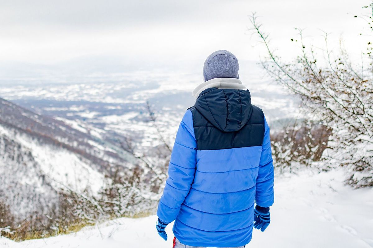 山の上から雪景色を眺める少年