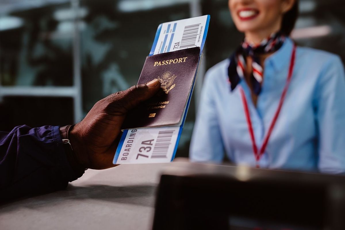 国際空港の航空会社のチェックインデスクで搭乗券とパスポートを持っているアフリカ系アメリカ人男性