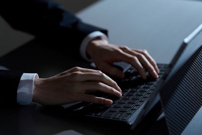 夜間にPCで作業している男性の手元