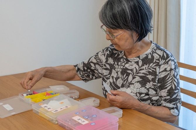 飲み忘れのないように、ピルケースに薬を仕分けているシニア女性