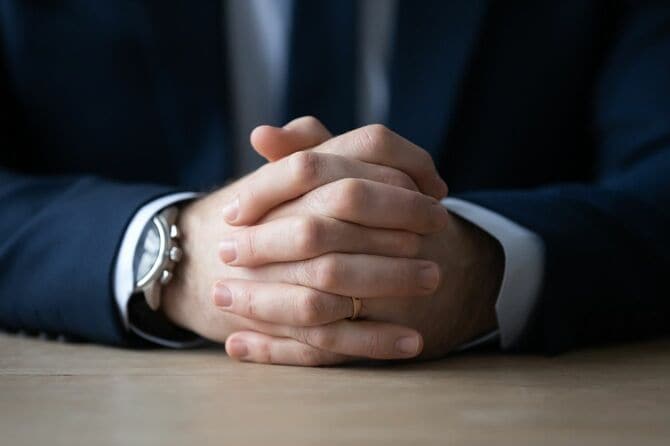 スーツで着席したビジネスマンの握りしめた手