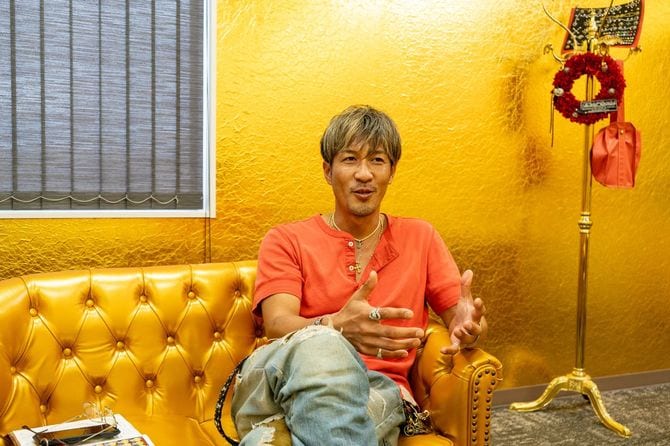 金箔の壁紙で覆われた社長室にて。「この部屋は来た人に驚いてもらう用で、いつもはみんなの横で仕事しとるんだわ」を坂口さん