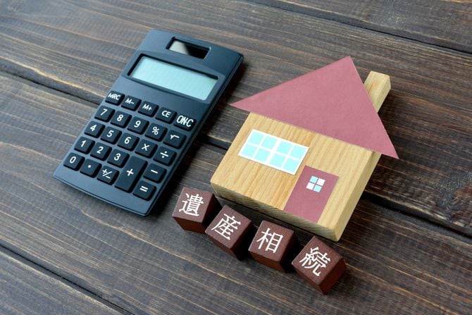 遺産相続と書かれたブロックと家のミニチュアと電卓