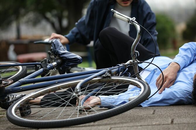 自転車事故の写真。倒れる男性と自転車を降りて声を掛ける男性