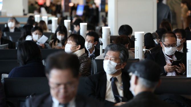 新型肺炎の感染防止のためにマスクを着けて飛行機の搭乗を待つ客たち＝2月17日、東京・羽田空港