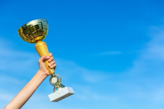 青い空を背景にトロフィーカップを持っている子供の手