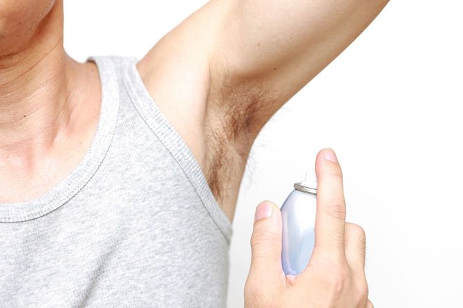 脇の下に制汗スプレーを使用する人