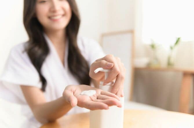 ボトルから保湿クリームを手に取る女性