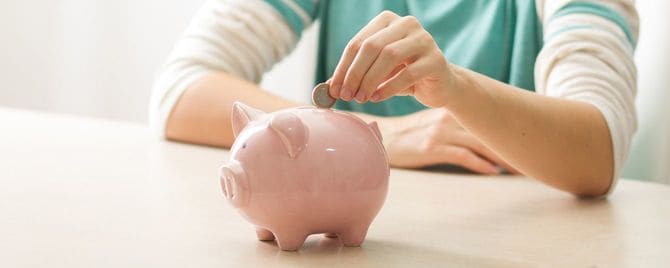 豚の貯金箱にコインを投入する手元