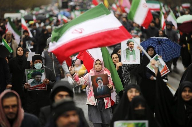 イランの首都テヘランで国旗を掲げながら行進する人々＝2026年3月13日（ゲッティ＝共同）