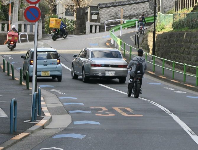 車道を走るフル電動自転車。ナンバープレートはなく、ペダルを漕がずに坂を上っていった