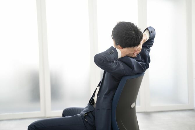 オフィスで手持ちぶさたにしていて、ストレッチをしている男性