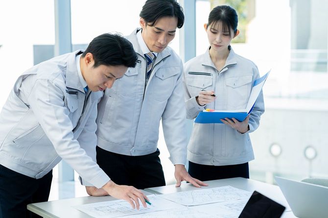 打ち合わせをする、作業着を着た3人のエンジニア