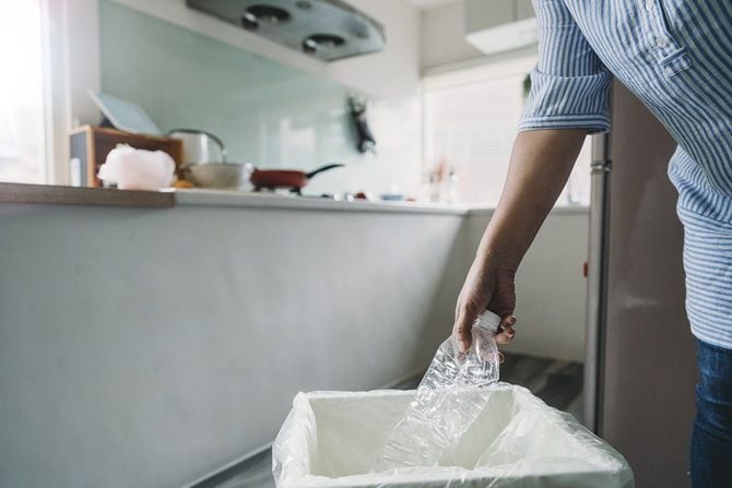 キッチンのゴミ箱にペットボトルを捨てる女性