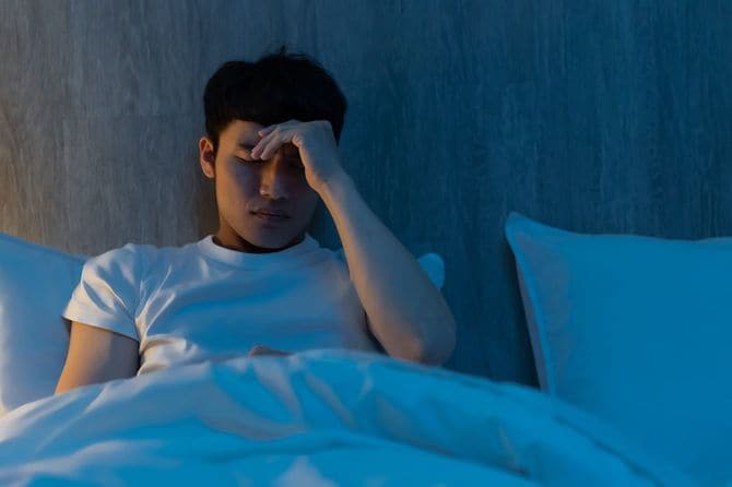 ベッドの上で憂鬱そうにしている男性