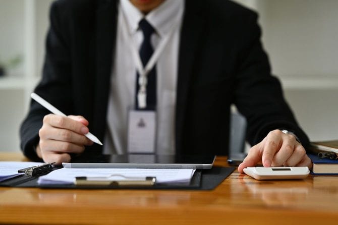 パソコンや電卓を使用するビジネスマン