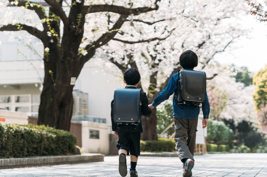 春の学校の前を歩く二人の小学生