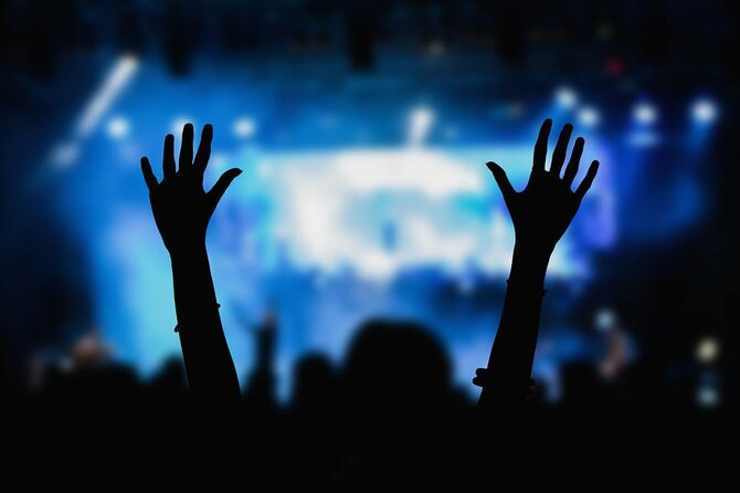 両手を上げてコンサートを楽しむ人
