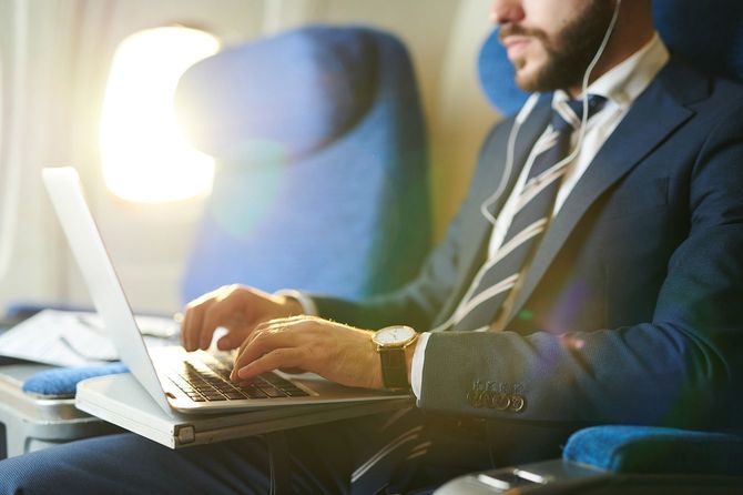 飛行機でファーストクラスの飛行中にラップトップを使用しているビジネスマン