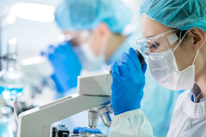 実験室で顕微鏡を使用する科学者チーム