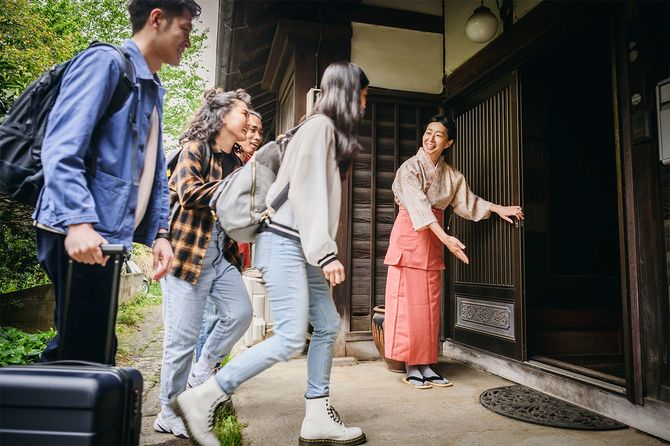 日本の伝統的旅館に到着する若い旅行者のグループ