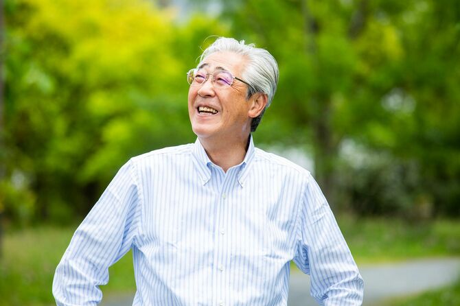 新緑の屋外で撮影された優雅な中年日本人男性の肖像画