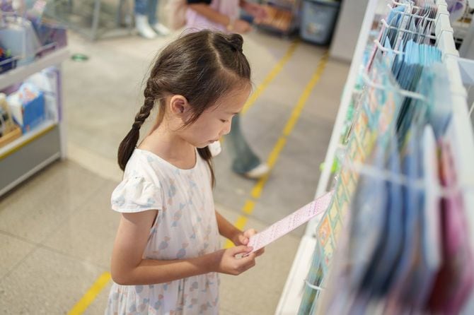文具コーナーでシールを手に取り見つめている女の子