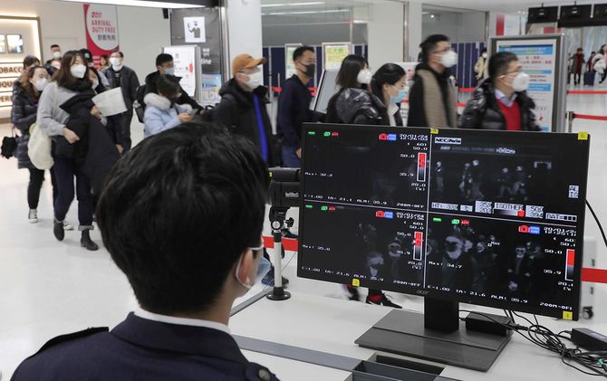 検疫所のサーモグラフィーで、到着した乗客の体温を確認する検疫官＝2020年1月24日、千葉・成田空港