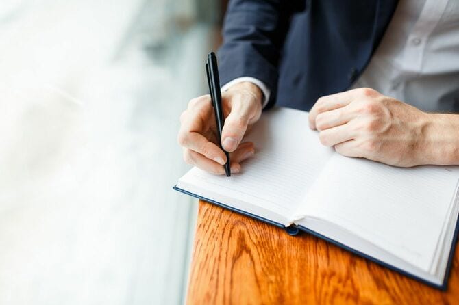 ノートの空白のページにペンで書き込む人