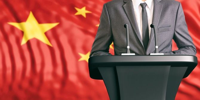 中国の国旗を背景にスピーチ