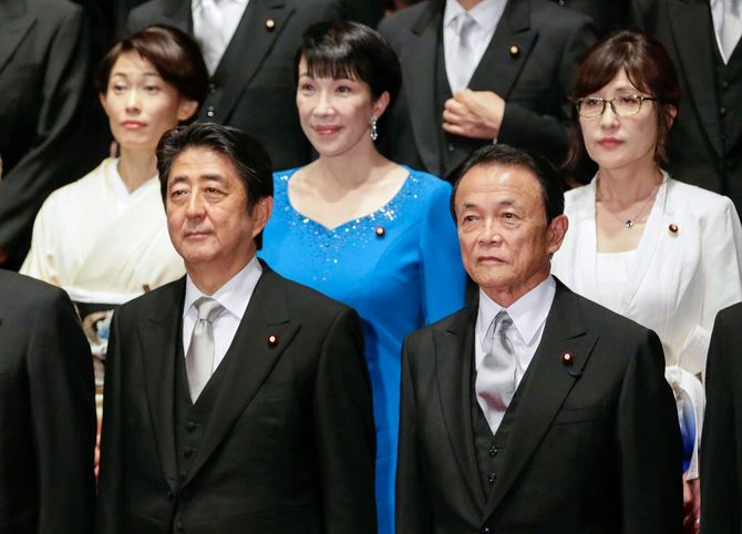 2016年8月3日、東京の首相官邸にて。安倍首相(当時)が行った内閣改造で新たに任命された稲田朋美防衛大臣(右上)、再任された高市早苗総務大臣(上中央)らと写真に納まる安倍晋三首相(左前)と麻生太郎財務大臣(右前)