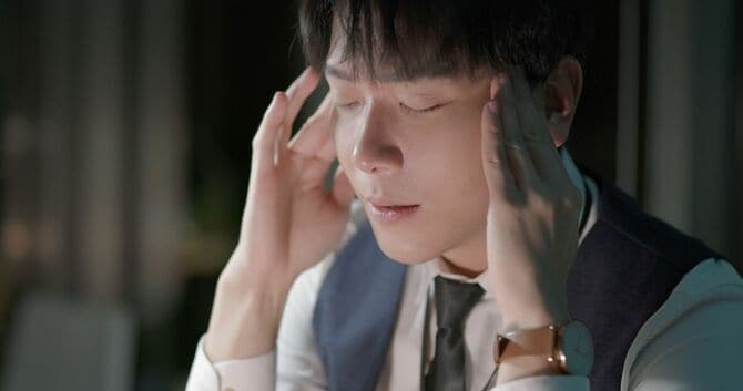 疲れてこめかみを抑える若いビジネスマン