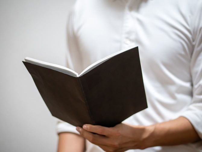 黒いノートを持ったシャツを着た男