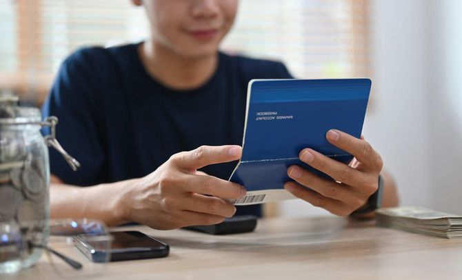 紙の通帳をみてほほ笑んでいる男性