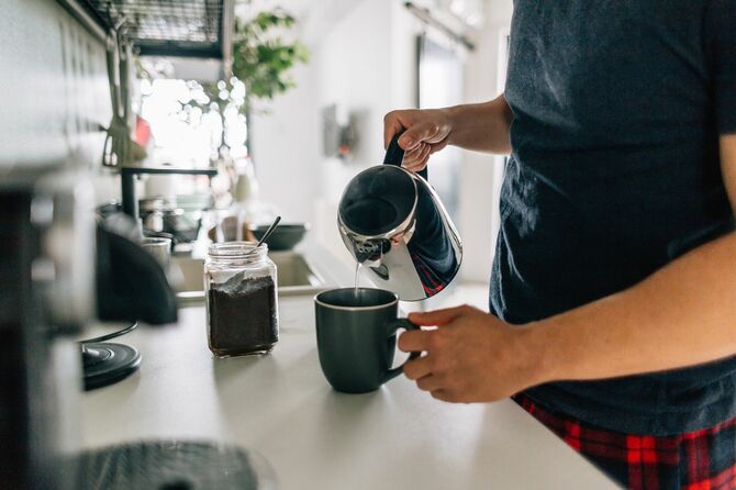 朝のキッチンでコーヒーを淹れる男性