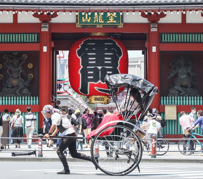 都道府県境をまたぐ移動が全面解禁後の初の週末を迎え、多くの観光客でにぎわう浅草・雷門の前を通過する人力車＝2020年6月20日、東京都台東区