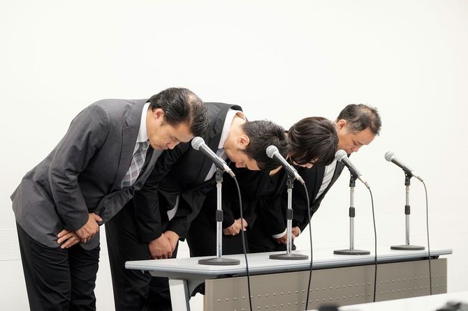 記者会見で謝罪をする人たち