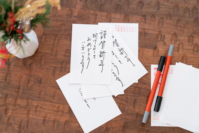 クリスマスの飾りつけがあるテーブルで年賀状の作成中