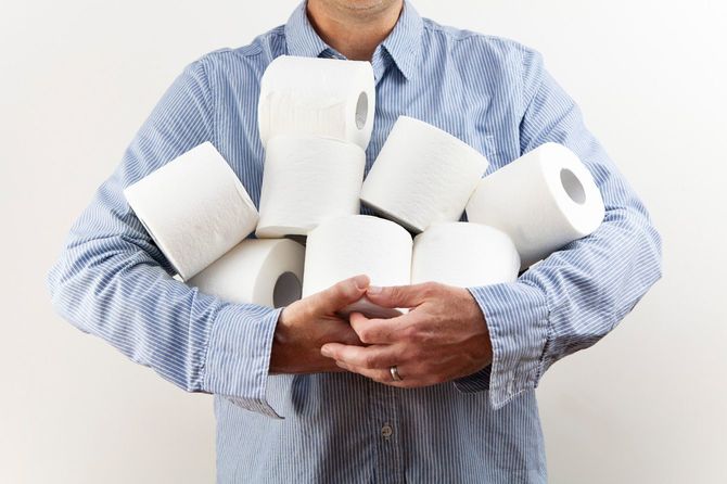 両手いっぱいにトイレットペーパーを抱える中年男性