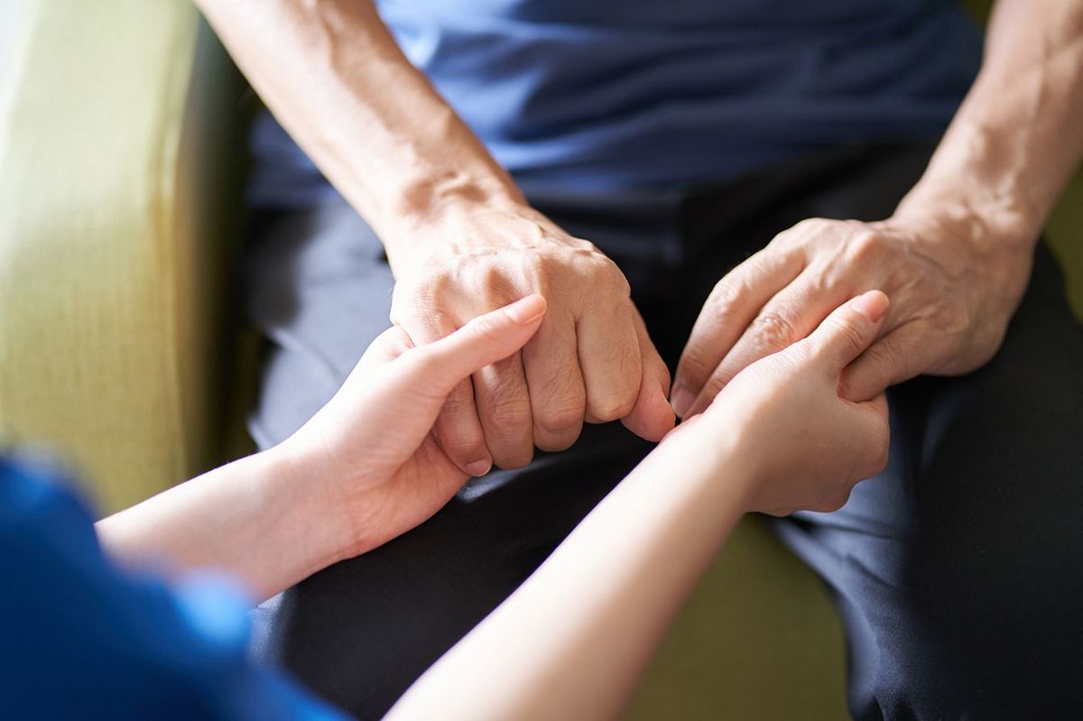 高齢者の手を握る介護者の手